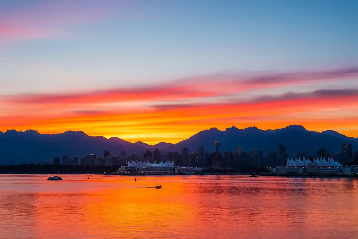 A photo of a beautiful sunset over the water in Vancouver with mountains in the background.