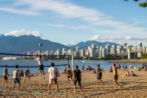 People playing volleyball on Kitsilano Beach with a view of the mountains and city skyline in the background