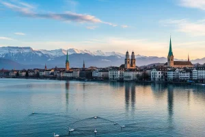 A photo of Lake Zurich with the city's spires and the Alps in the background