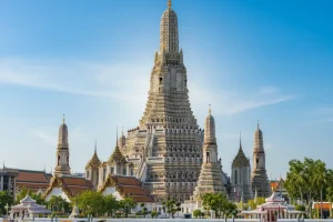 The central prang of Wat Arun (Temple of Dawn) shimmering against a blue sky.