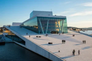A photo of the Oslo Opera House on the waterfront, with people walking on its roof.