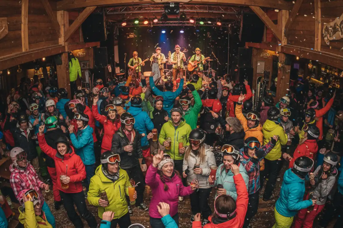 A lively, crowded Après-ski bar in Ischgl with people dancing in ski gear with drinks.