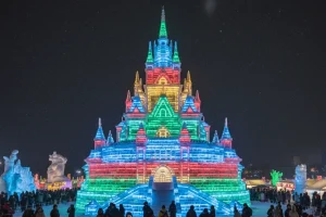 A huge, intricate ice sculpture illuminated with colorful lights at the Sapporo Snow Festival in Japan