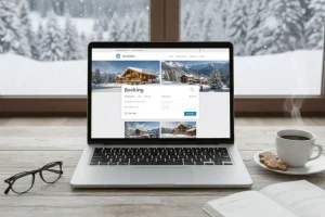 A laptop showing a booking website open on a coffee table in front of a window with snowy view