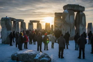 People gathering at sunrise at the ancient stone circle of Stonehenge on the shortest day of the year, waiting for the first rays of returning sunlight.