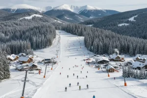 A view of the Poiana Brașov slopes with skiers descending, and the thick forests of the Carpathian Mountains surrounding the resort.