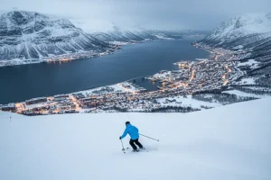 A skier coming down a slope at Narvikfjellet with the stunning view of the deep blue fjord and the city of Narvik below.