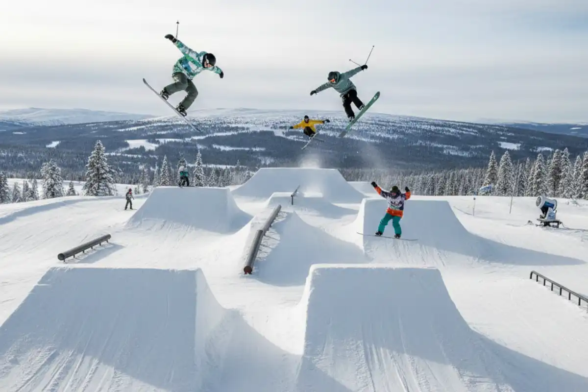 Skiers and snowboarders performing jumps and tricks in a well-maintained snow park at Vemdalen, Sweden.