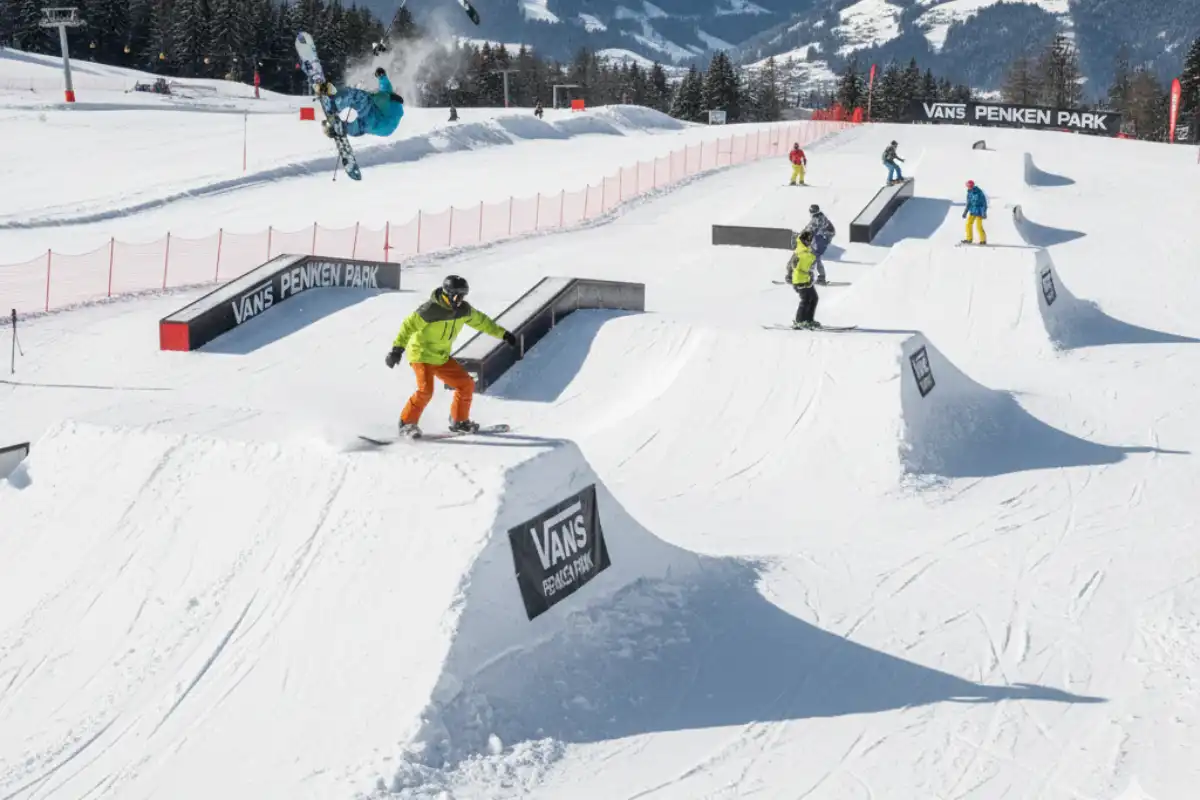 Skiers and snowboarders performing tricks on the large jumps and features within the expansive Vans Penken Park in Mayrhofen.