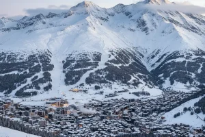A panoramic view of Davos city nestled in the valley, with the towering Parsenn ski mountain in the background.