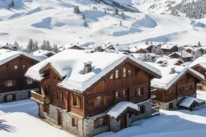 The traditional wooden chalets of Méribel Village covered in snow, with ski slopes in the surrounding French Alps.