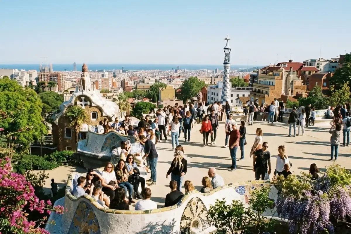 Crowds in Park Güell enjoying the panoramic view of Barcelona during a sunny spring day.