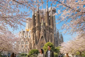 The Sagrada Familia framed by blooming spring trees and a bright blue sky in Barcelona.