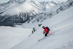 A skier descending the steep, challenging upper slope from Lomnické sedlo in Tatranská Lomnica with dramatic mountain views.
