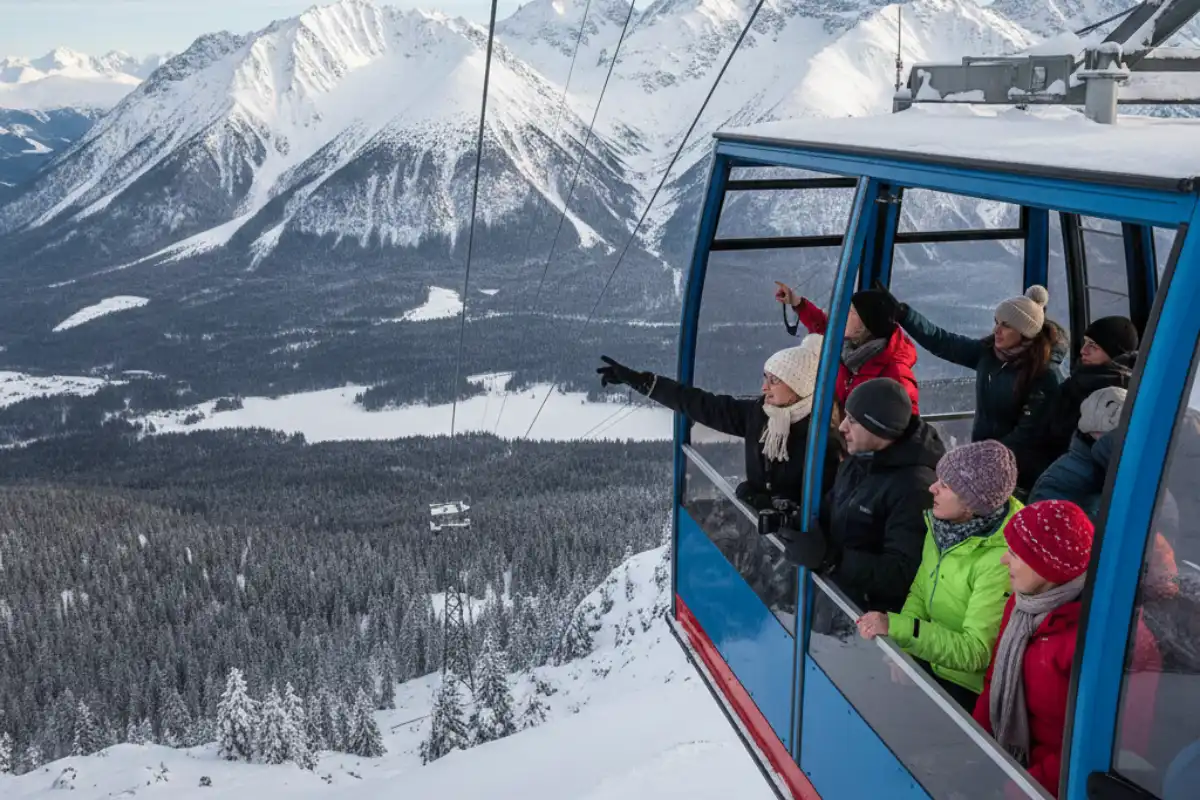 Tourists riding the cable car up to Skalnaté Pleso with a panoramic view of the High Tatras mountains and the valley below.