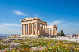 The ancient Parthenon temple standing tall against a bright blue sky with vibrant wildflowers blooming in the foreground on the Acropolis hill