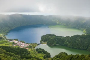 Lush green volcanic hills of Sete Cidades framing twin blue and green lakes under a soft spring mist