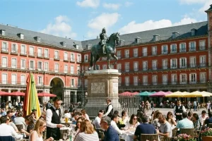 Vibrant terrace dining at Plaza Mayor in Madrid with historic red buildings and sunny spring skies