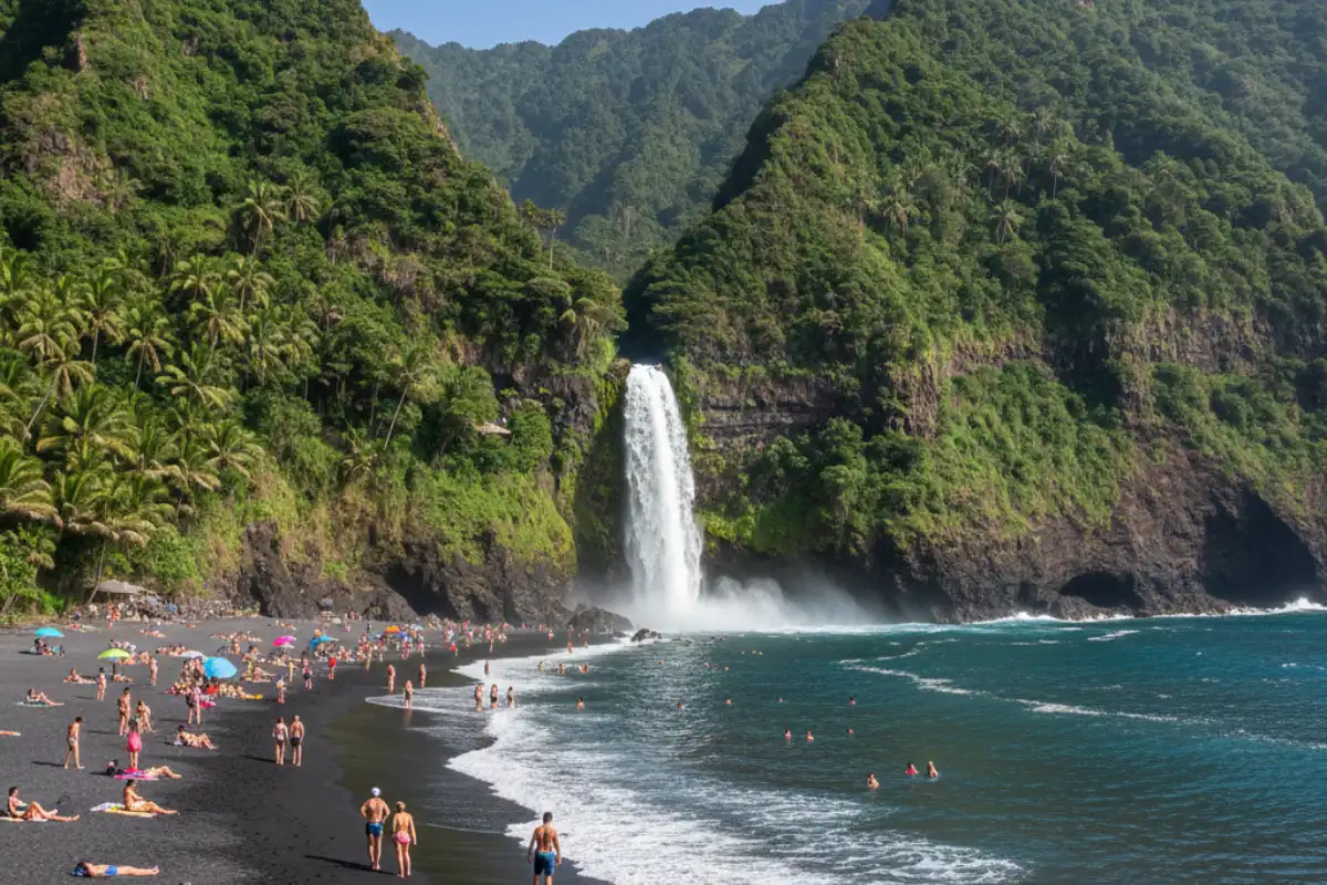 The black volcanic sand of Seixal Beach framed by steep green mountains and a cascading waterfall hitting the ocean
