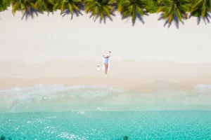 Serene aerial view of a person relaxing on a turquoise beach shore