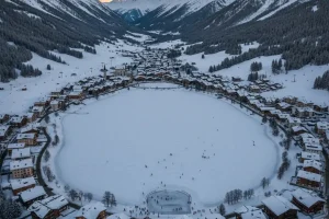 A snowy, high-altitude view of the village of Arosa surrounded by mountains, with the frozen lake visible.