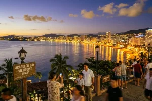 The sweeping golden curve of Acapulco Bay at twilight with shimmering city lights reflecting on the calm Pacific waters